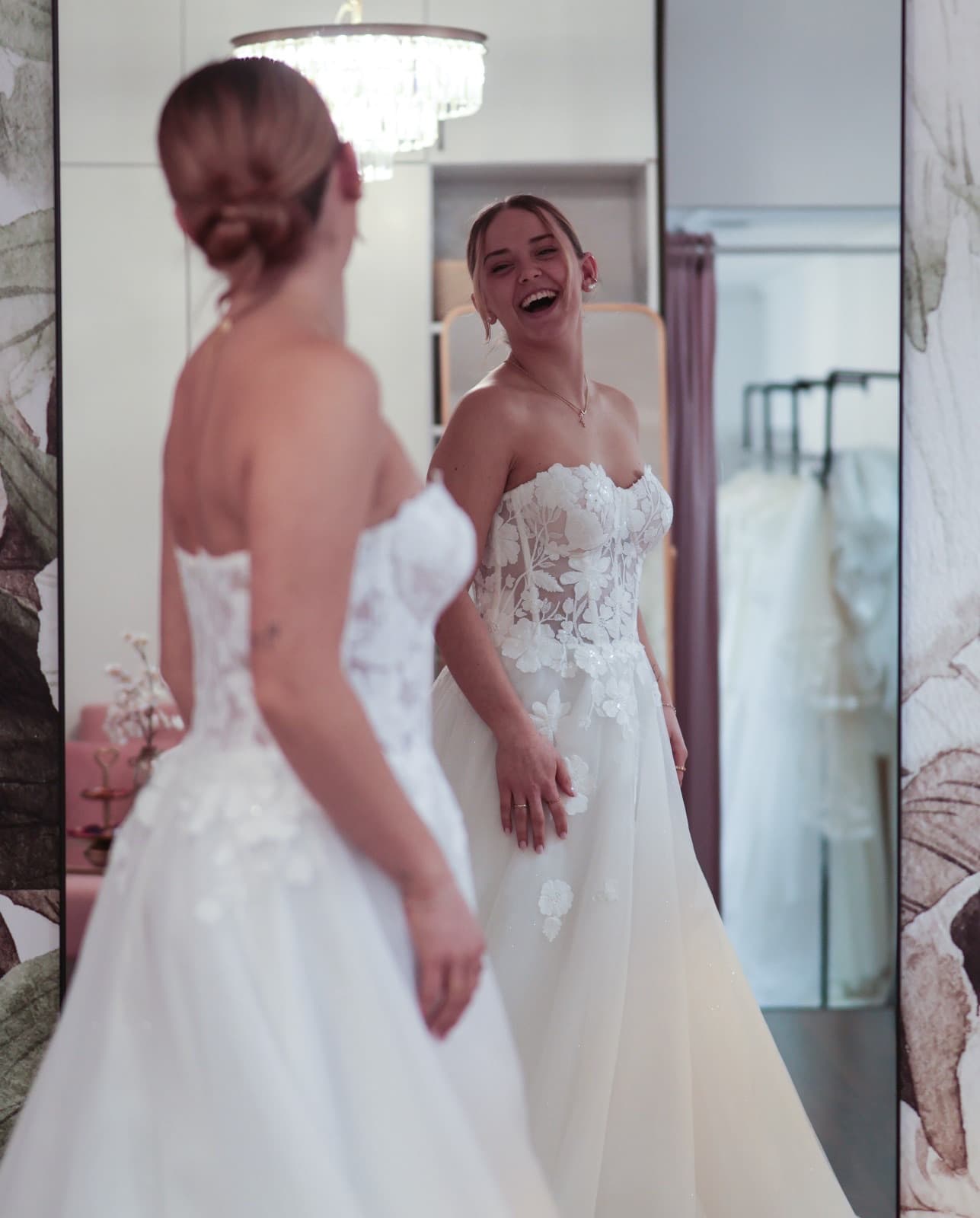 Braut lacht glücklich vor dem Spiegel bei der Brautkleid-Anprobe im Atelier Liebesgeschichte in Königsbach-Stein